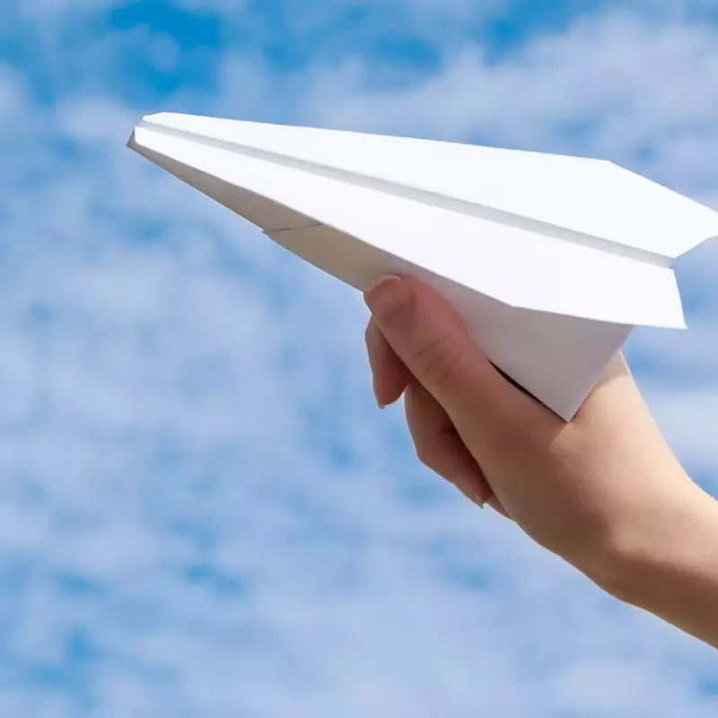 paper airplane with woman hand in sky